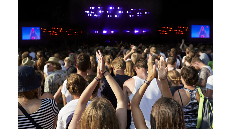 Women clapping hands at large concert