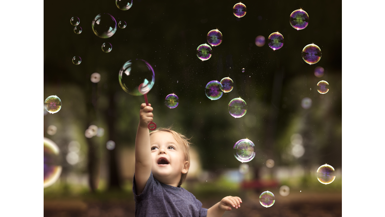 2 Year Old Fraternal Twin Boy Hold a Bubble Want and Plays with Floating Bubbles in a Park