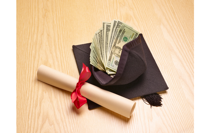 Rolled diploma and mortar board with US banknotes inside, studio shot