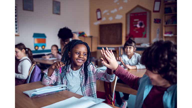 School kids high-fiving in the classroom