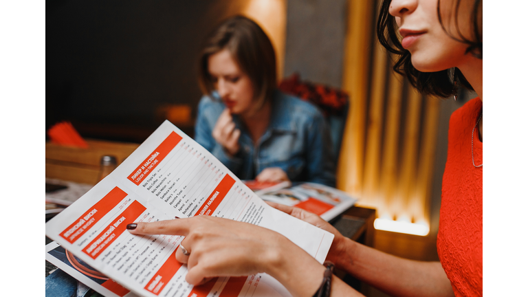 girlfriends in cafe night club choose the food menu