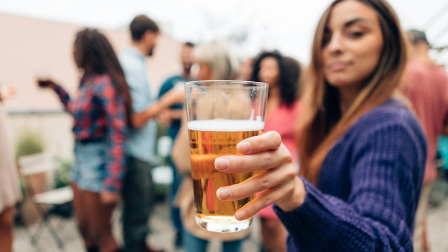 Female Hand Holding Beer At The Party - Girl Offering Drink Or Cheer With A Pint At The Rooftop