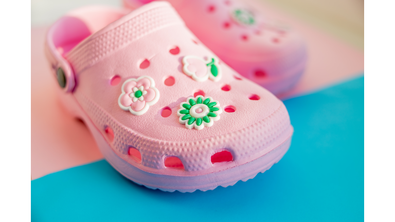 Colorful children's rubber sandals isolated on the blue background. pink rubber shoes.Children's shoes