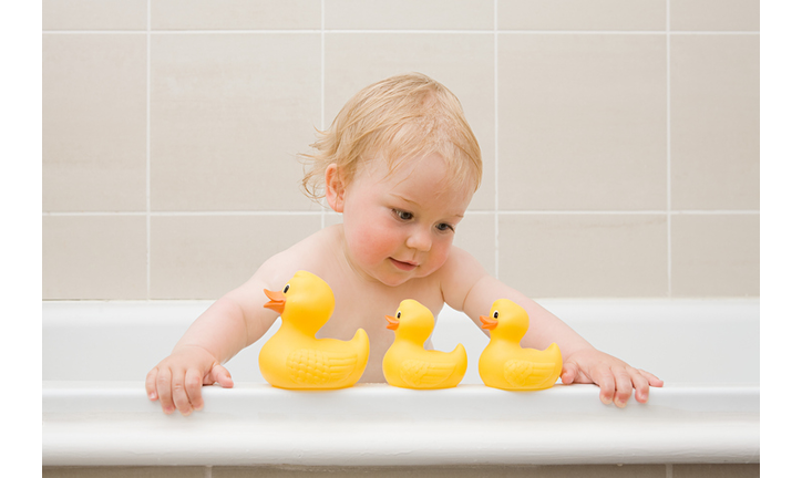 A baby boy looking at a row of rubber ducks