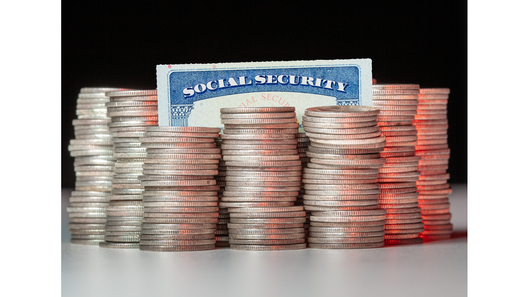 Close-Up Of Coins Stacked By Social Security Card On Table Against Black Background