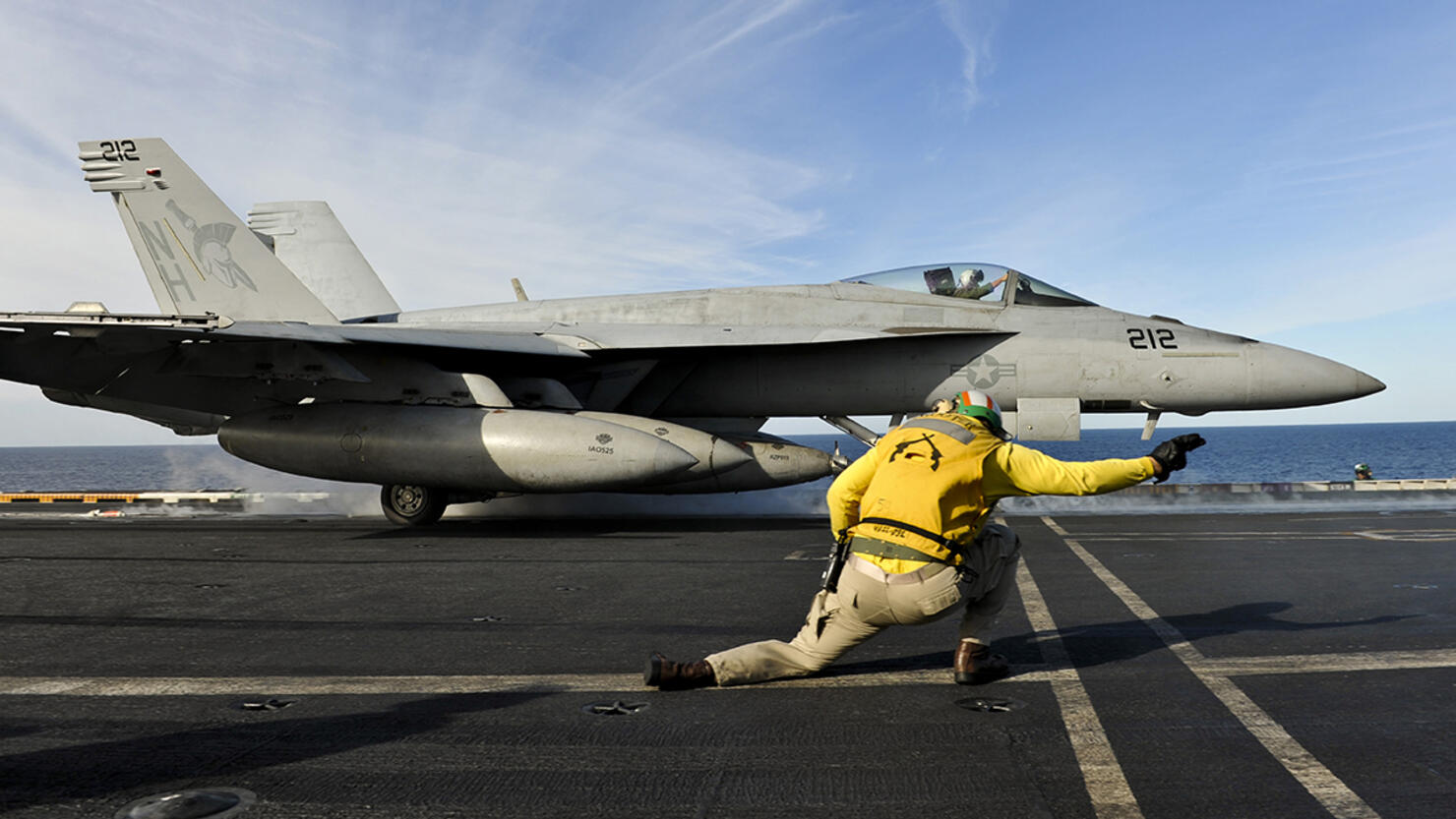 A shooter signals to launch an F/A-18E Super Hornet aboard USS Nimitz.