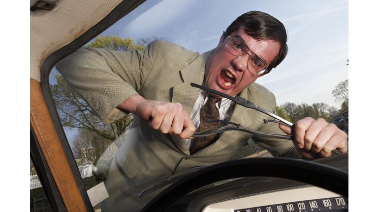 Man breaking windshield wiper and yelling, view from car, portrait