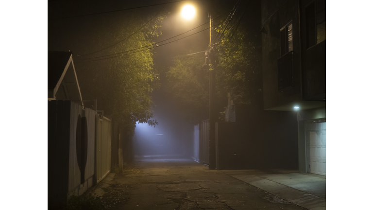 A dark alleyway with streetlights.