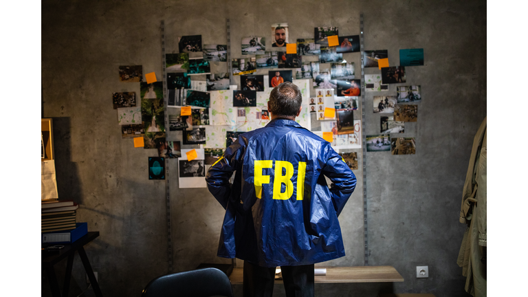 FBI detective looking at wall full of evidences and crime scene pictures