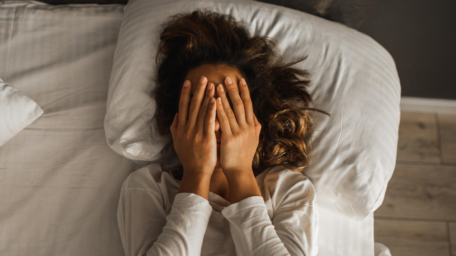 Woman in depression closed face with hands and crying in bed. Melancholy mood, mental health. Life problems