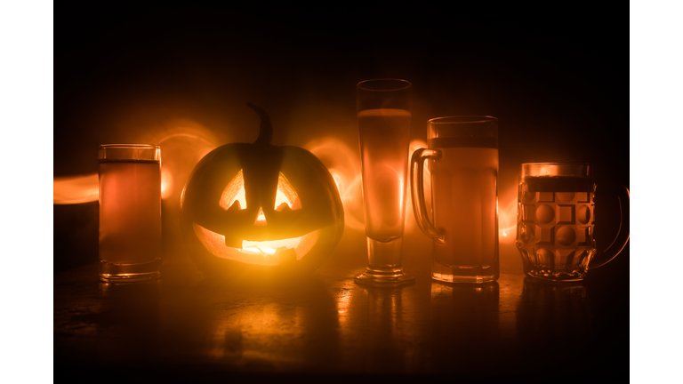 Glass of cold light beer with pumpkin on a wood background for Halloween. Glass of fresh beer and pumpkin on a dark toned foggy background