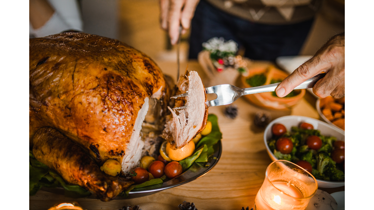 Close up of unrecognizable man carving roasted Thanksgiving turkey.