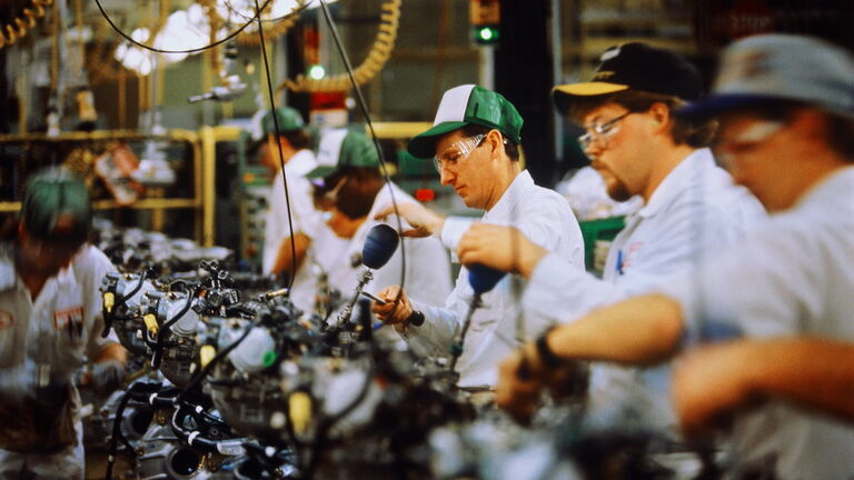 Car engine assembly, workers adjusting engine block valve