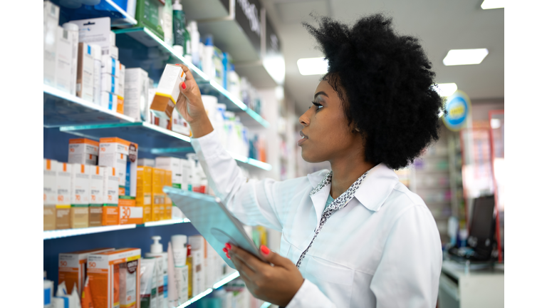 Young pharmacist checking the shelves with a digital tablet at the pharmacy