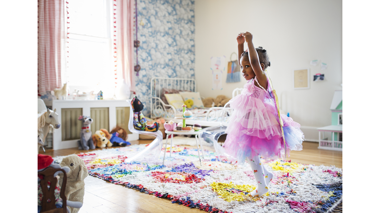 Full length of girl in fairy costume dancing at home