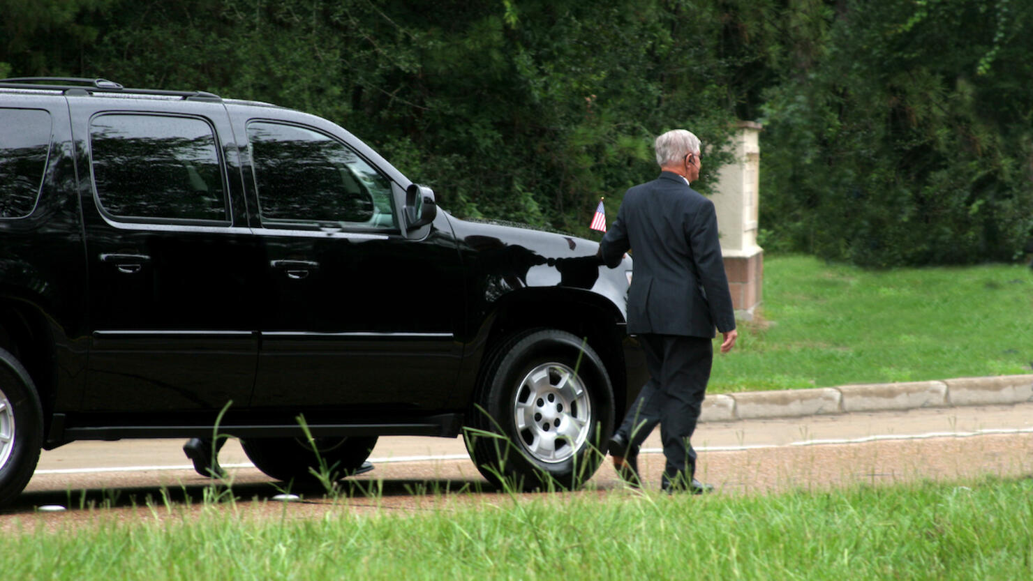 Secret Service men walking beside black SUV. Motorcade.
