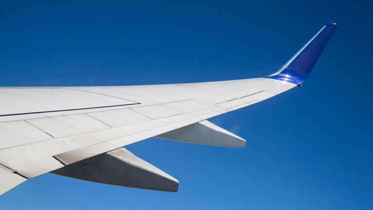 Close-Up Of Airplane Wing Against Clear Blue Sky