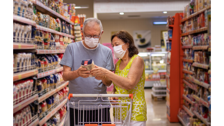 A senior couple shopping at the market with protective masks.