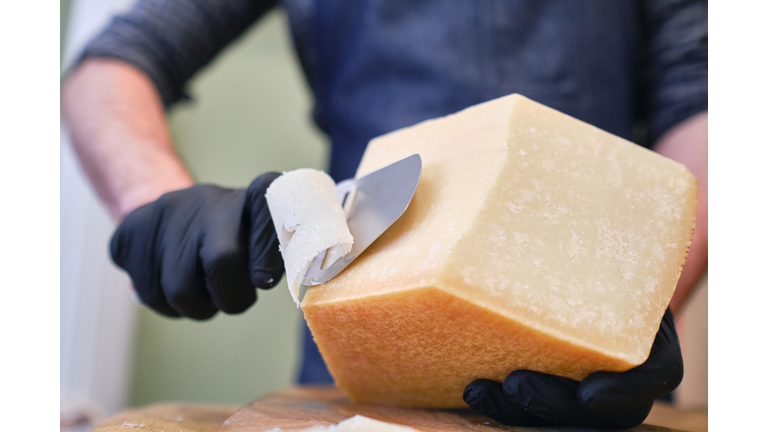 Young worker slicing cheese in shop.selective focus