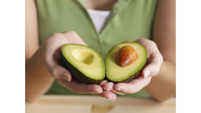 Woman holding halved avocado