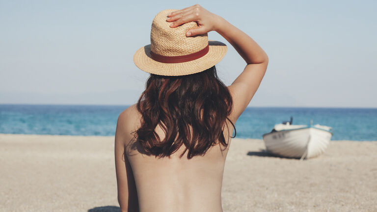 Greece, young woman on the beach looking at the sea