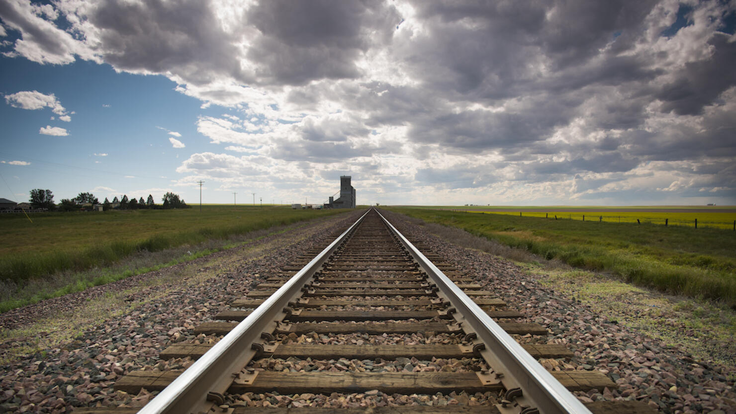 railroad tracks recede to the horizon, dark summer sky approaching