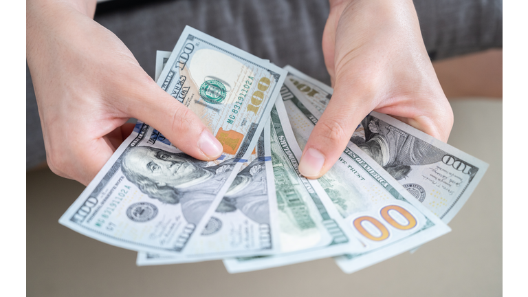 Close up of someone hands holding and counting American dollar banknotes in her hand.