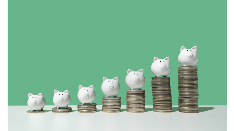 Little piggy banks on ascending stacks of coins