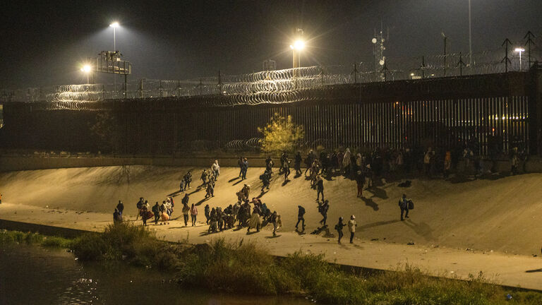 Migrants wait on the Mexican bank of the Rio Grande in Ciudad Juarez