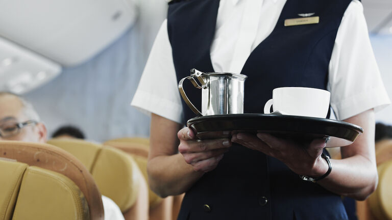 Flight attendant holding tray with coffee, mid section