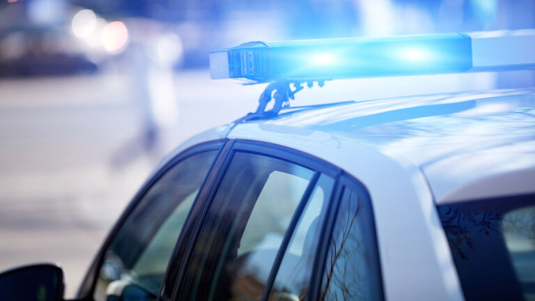 Police car with blue lights on the crime scene in traffic urban environment.