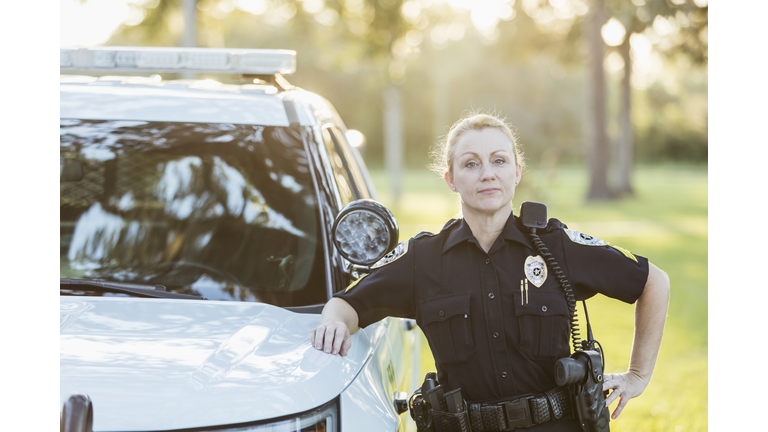 Policewoman standing beside police squad car