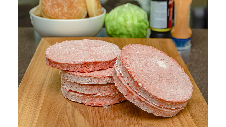Frozen beef burger patties are placed on a wooden cutting board before cooking. Freezing in the freezer.