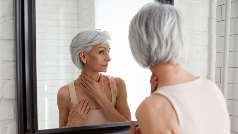 Elderly woman at mirror in bathroom