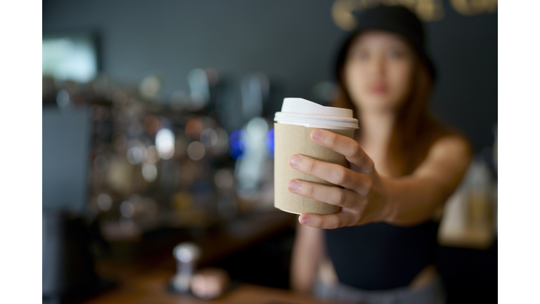 Woman barista serving coffee in takeaway paper disposable cups