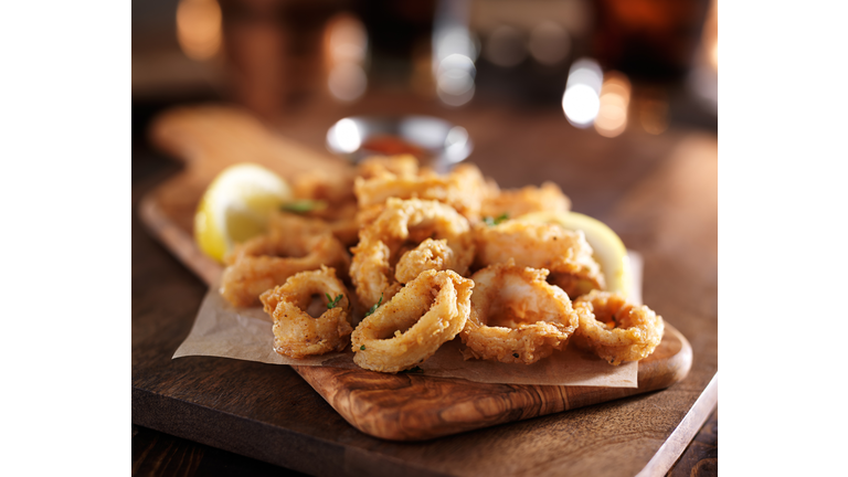 fried calimari rings on wooden tray with dipping sauce