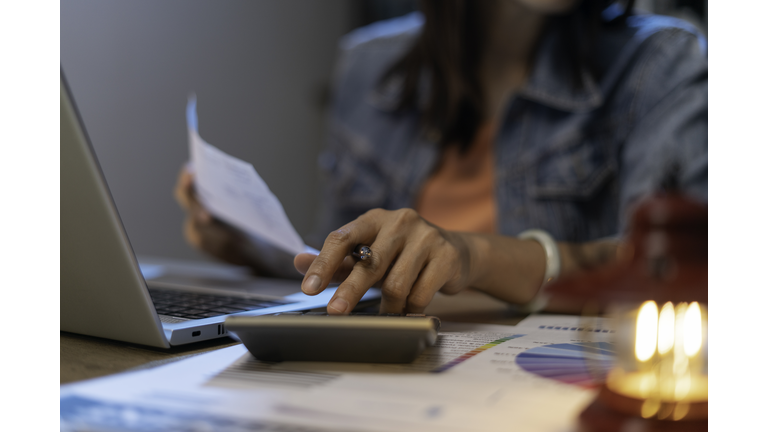 Close up of woman planning home budget and using calculator.