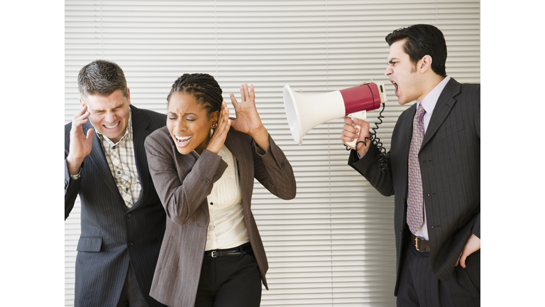 Businessman shouting through bullhorn at co-workers