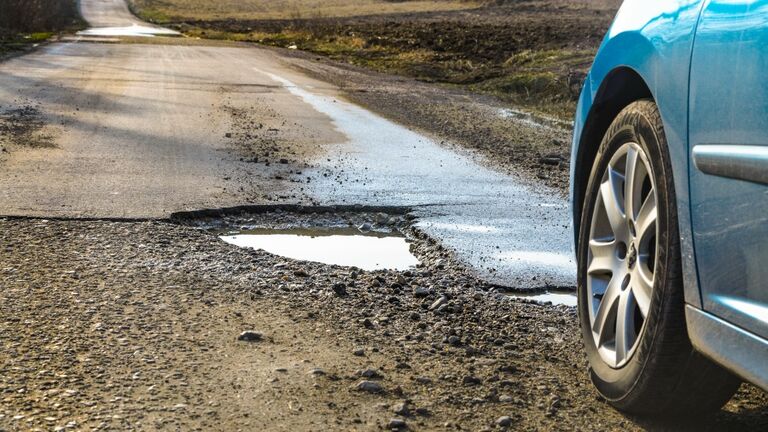 Car and winter pothole on open road