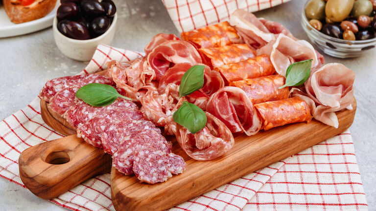 Food antipasto prosciutto ham, salami, olives and bread and Tomato and basil bruschetta Charcuterie board. Two glasses of white wine or prosecco
