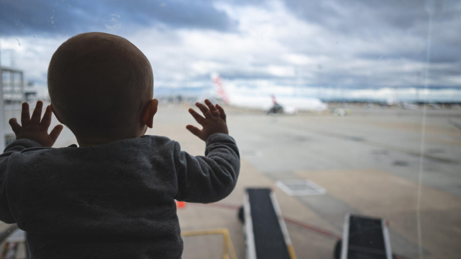 One year old baby looking through an airport window