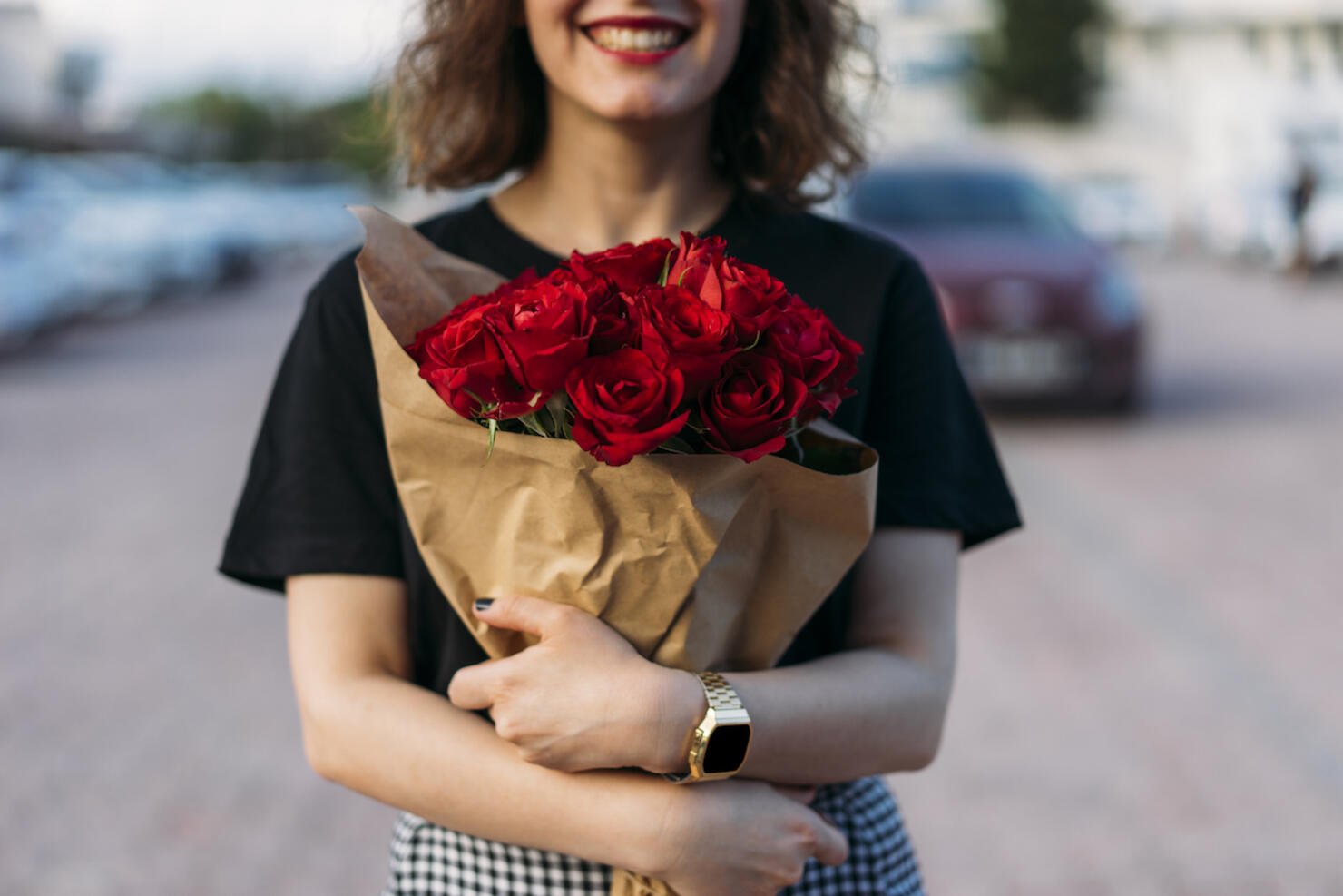 Young woman holding beautiful red flowers bouquet