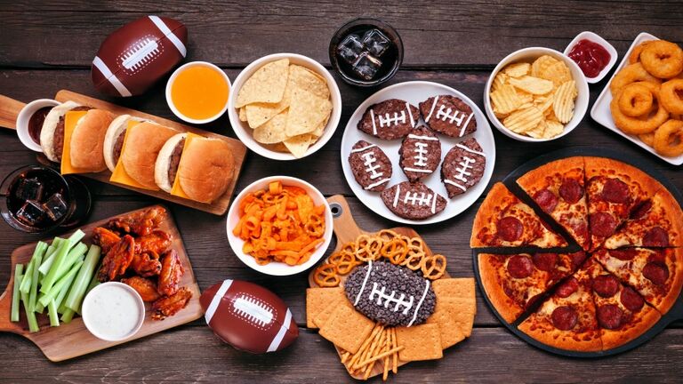 Super Bowl or football theme food table scene, top view on dark wood