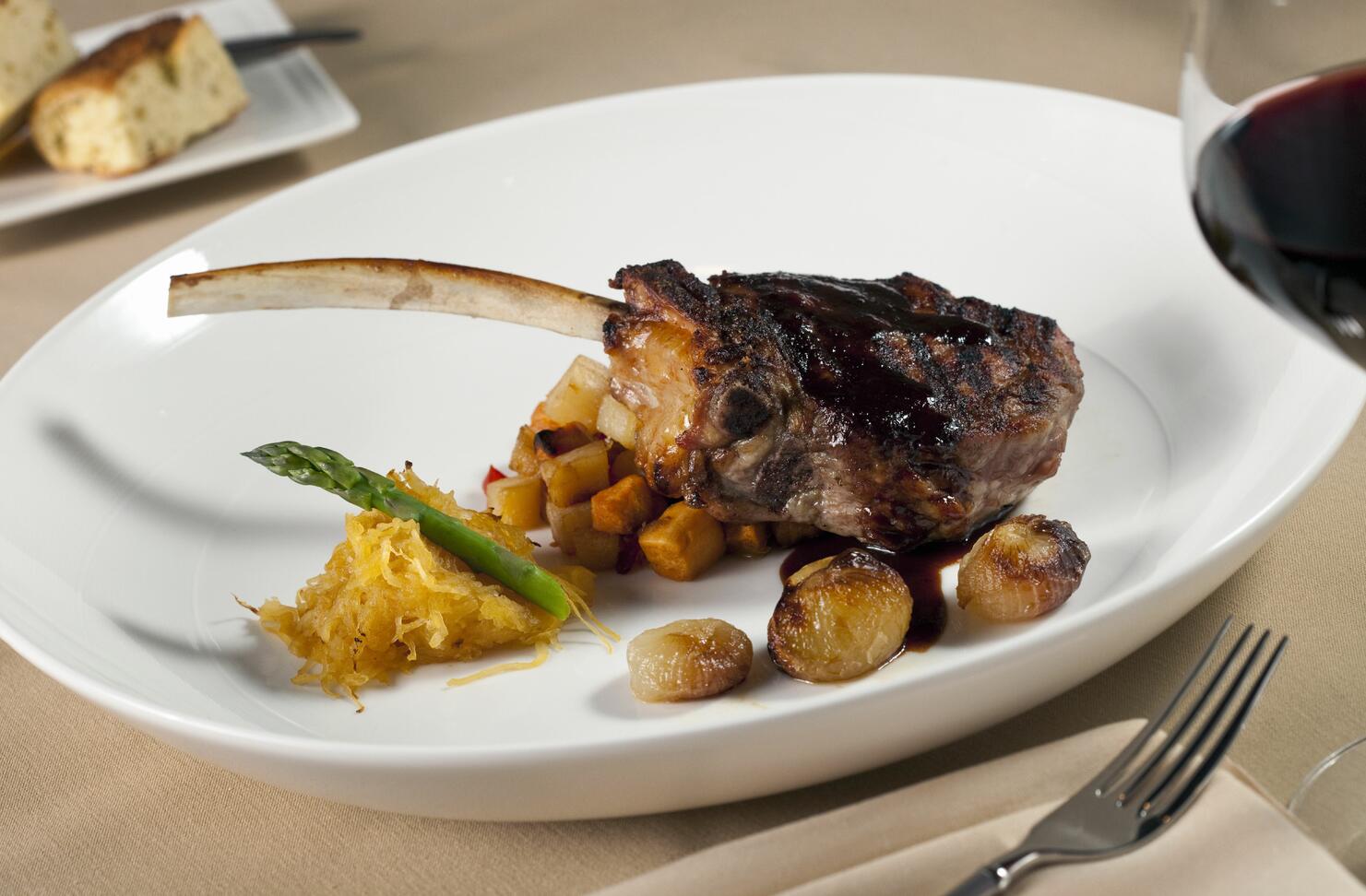 Bone in rib eye steak with red wine on white plate