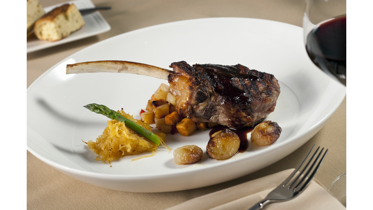 Bone in rib eye steak with red wine on white plate