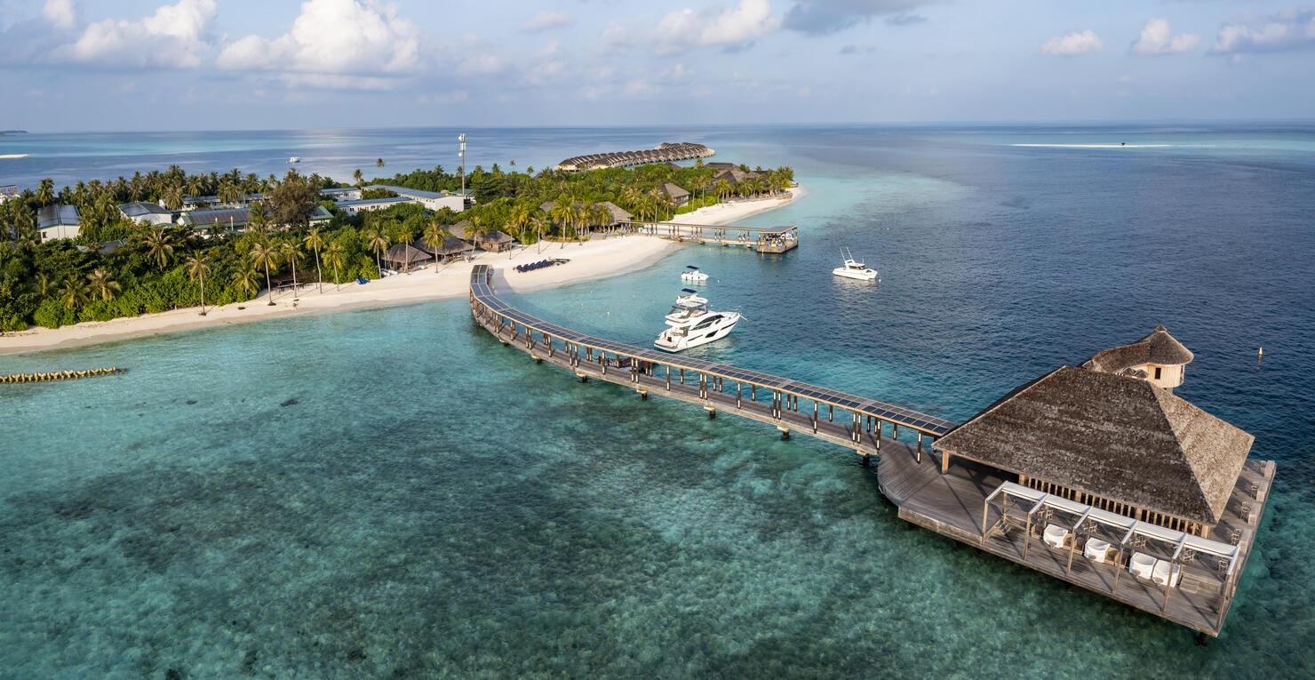 Aerial view of sea with tourist resort under cloudy sky at Maldives