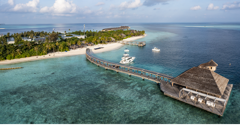 Aerial view of sea with tourist resort under cloudy sky at Maldives