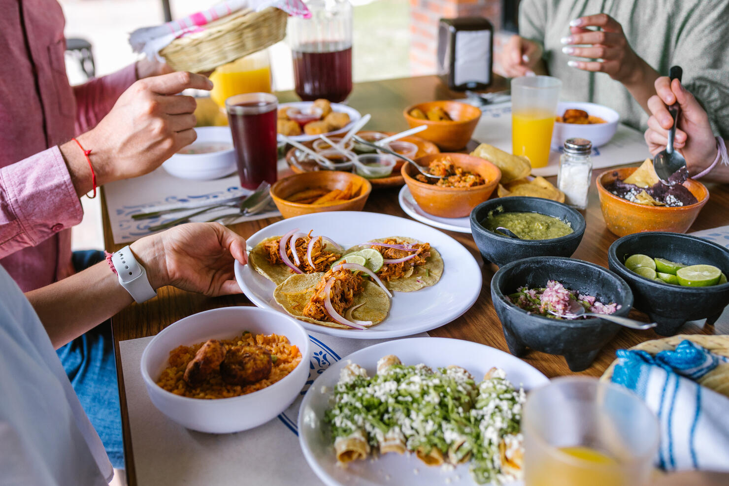 group of Friend eating Mexican Tacos and traditional food, snacks and peoples hands over table, top view. Mexican cuisine