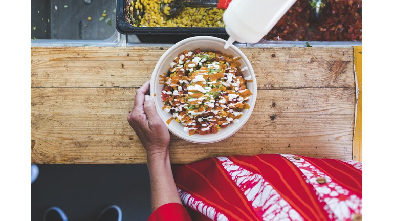 Midsection of female customer with fresh Tex-Mex in bowl at food truck