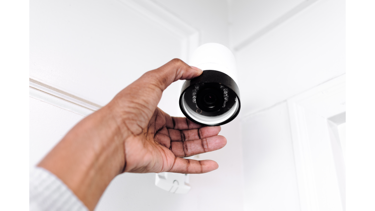 Woman Adjusts Outdoor Security Camera